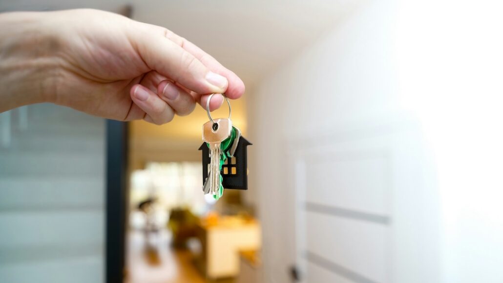 jakub-zerdzicki-bqUZEAeWuok-unsplash | Home Alarms Canada Holding house keys in front of an open door